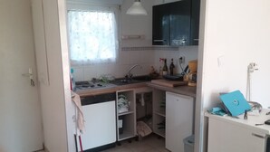 A compact kitchen with a dishwasher, sink, and cabinets. - T2 rez de Jardin 50m2 Bord de mer (Frontignan plage)