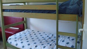 A bunk bed with a polka dot bedspread and a red bench. - T2 rez de Jardin 50m2 Bord de mer (Frontignan plage)
