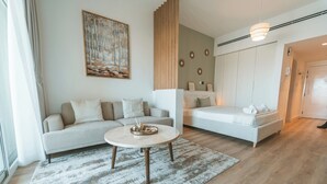 Un salon moderne avec un canapé, une table basse et un lit. Il y a un tableau accroché au mur et un panneau en bois sur le mur.