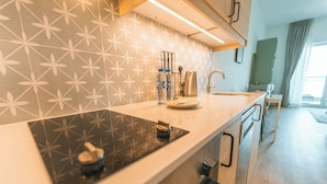 Une cuisine moderne dotée d’une plaque de cuisson à induction noire, d  ’appareils électroménagers en acier inoxydable et d’un crédence décorée.