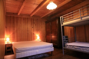 Een houten kamer met twee stapelbedden, een houten plafond en twee bedlampjes.