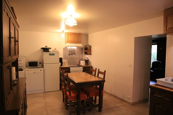 Cocina compacta con una mesa de comedor, sillas, microondas, refrigerador, estufa y lavabo.