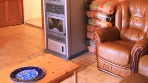 A wooden interior with a fireplace, a map on the wall, a leather chair, and a table with a plate.