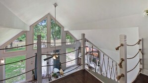 A spacious room with a high ceiling, large windows, and a wooden staircase. - Cozy Whispering Hideaway- Indulge in serenity and unwind in nature. (Ponchatoula)