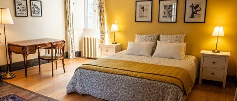 A bedroom with a bed, bedside tables, a desk, and chairs.