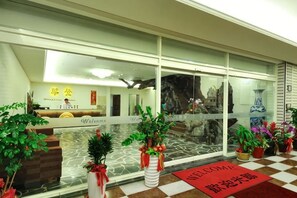 A hotel reception area with a glass wall, reception desk, and potted plants. - Huadon Resort Hotel (Hualien)