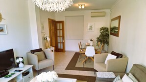 Un salon comprenant un téléviseur, un canapé, une table basse et un coin repas avec une table et des chaises.