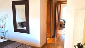Une chambre d’hôtel comprenant un lit, un bureau, une chaise, un miroir et une porte donnant sur une autre pièce.