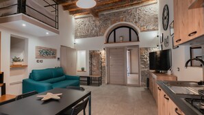 A modern kitchen with a stone wall, wooden cabinets, and a built-in TV. - Katrin House Alla Marina di Cefal by Wonderful Italy (Cefalù)