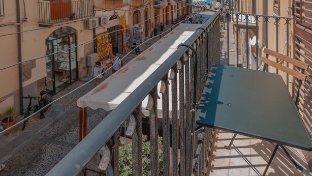 A narrow street with buildings on both sides, balconies, and a clear view of the sea. - Katrin House Alla Marina di Cefal by Wonderful Italy (Cefalù)