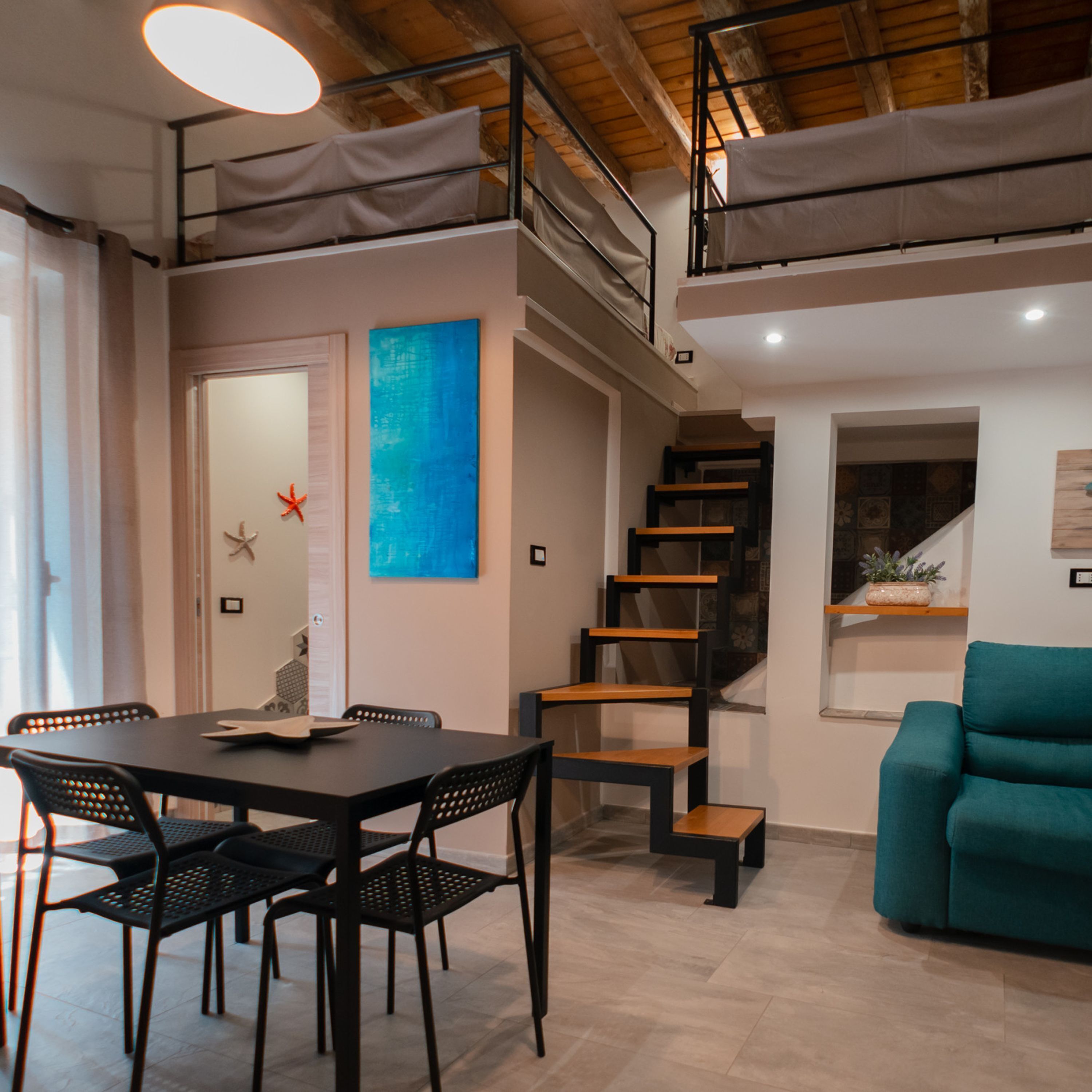 A modern interior with a dining area, staircase, and a sofa.