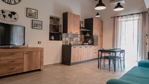 A modern kitchen with wooden cabinets, a built-in oven, and a dining area with a table and chairs. - Katrin House Alla Marina di Cefal by Wonderful Italy (Cefalù)