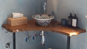 A bathroom with a round mirror, a sink, and a woven basket. - Monte da Urze (Aljezur)