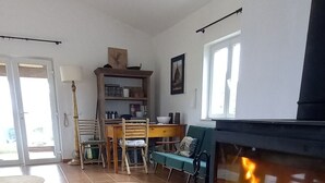 A living room with a fireplace, a dining area, and a view of the outside. - Monte da Urze (Aljezur)