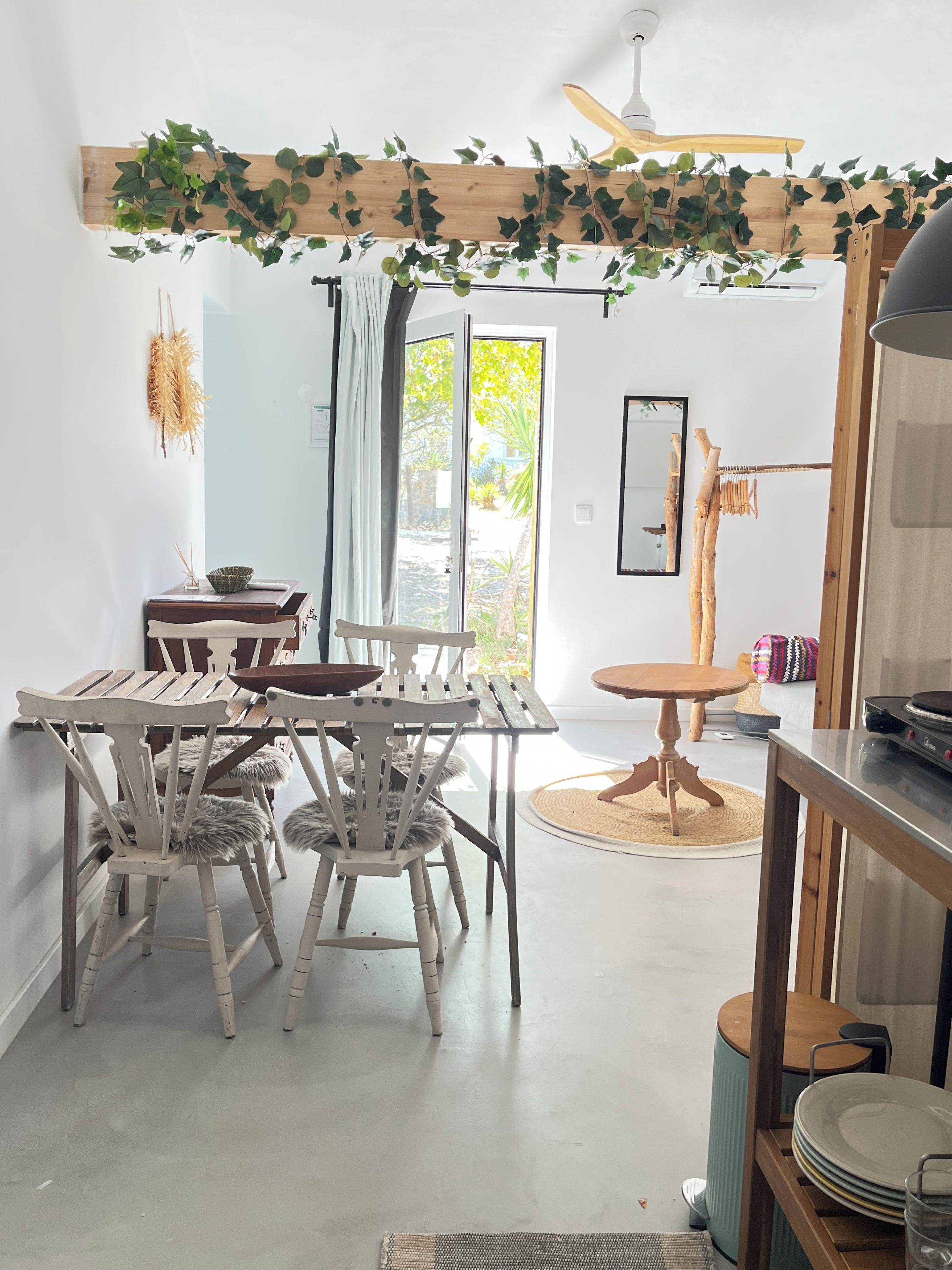 A dining area with a wooden table and chairs, a ceiling fan, and a view through a glass door.
