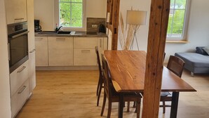Een moderne keuken met houten kastjes, een inbouwoven, een spoelbak en een raam.