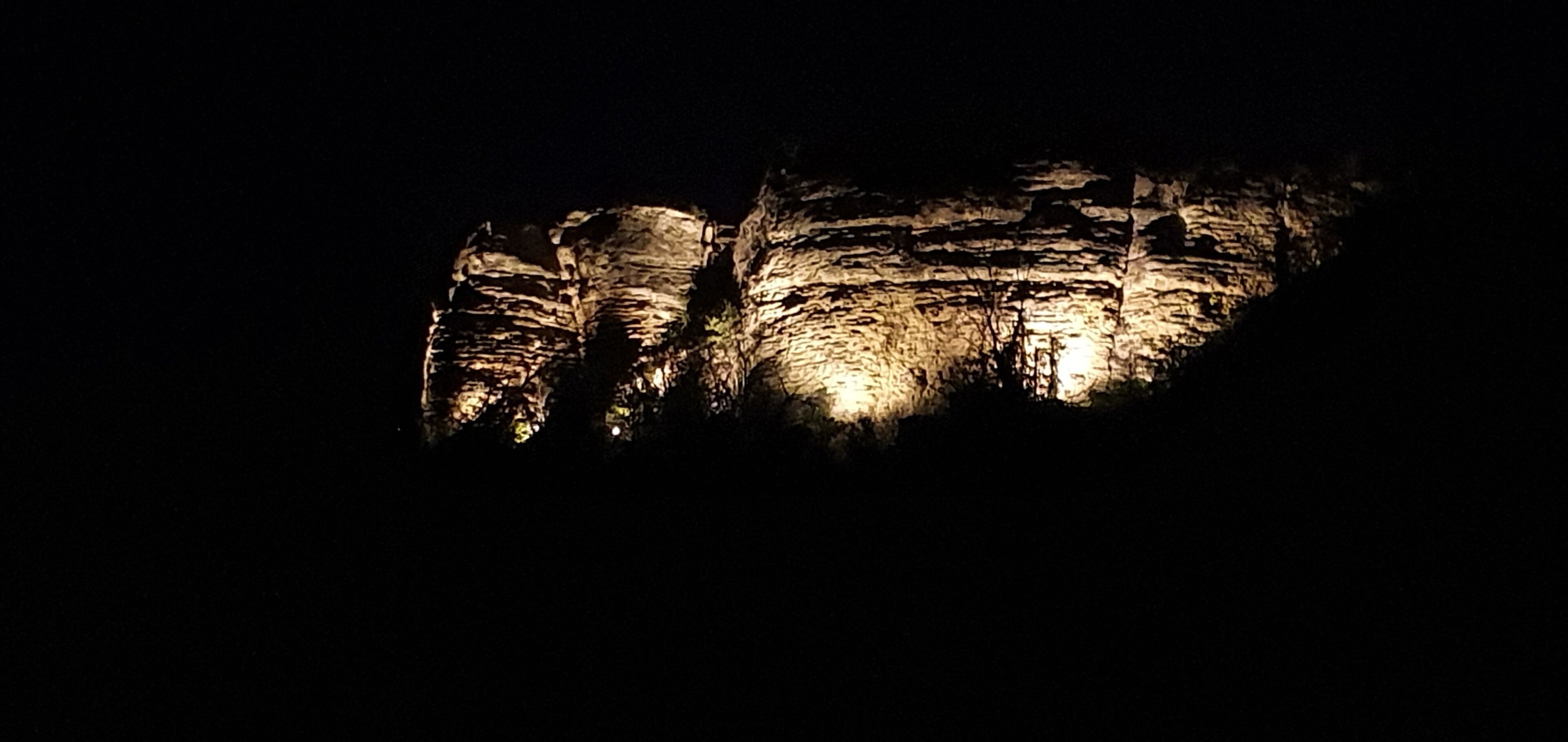 A large, illuminated rock formation at night.