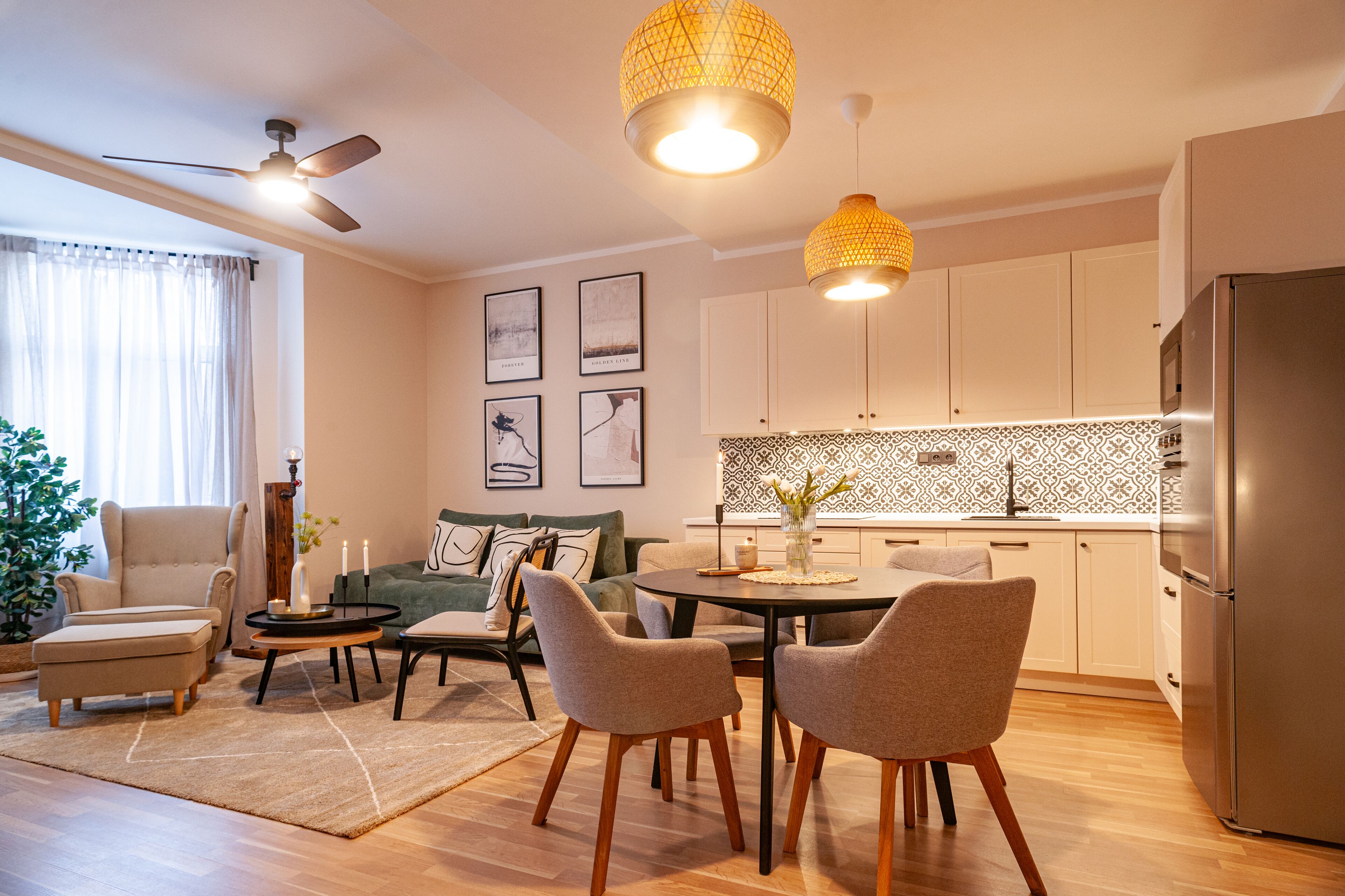 Una sala de estar moderna con un sofá, sillas, una mesa de centro y una mesa de comedor. Se observa una zona de cocina con armarios y un refrigerador.
