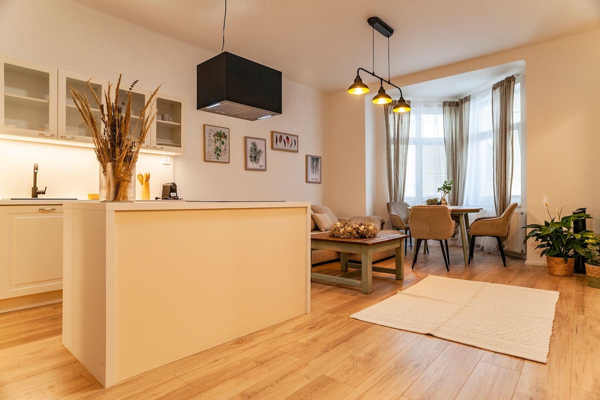 A modern kitchen with a central island, a dining area with a table and chairs, and a living space with a sofa and a coffee table.