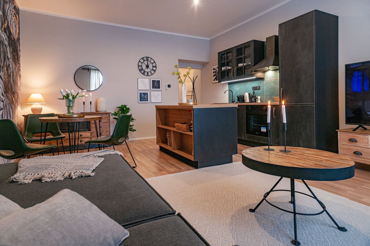 A modern living room with a sofa, a coffee table, and a dining area with chairs and a table.