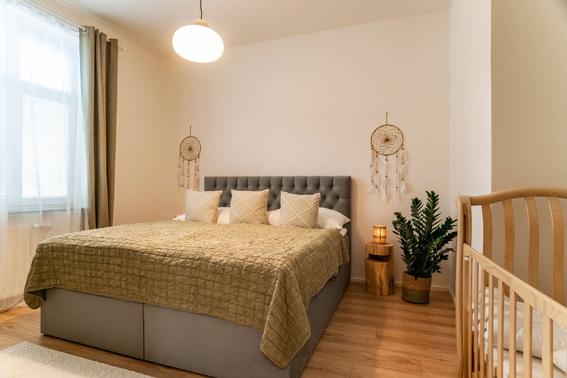 Ein Schlafzimmer mit einem Bett, Nachttischen, einem Hängeleuchter und zwei Traumfängern.