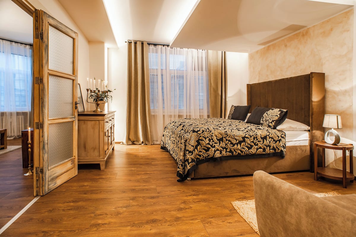 A bedroom with a large bed, a wooden dresser, a nightstand, and a chair.
