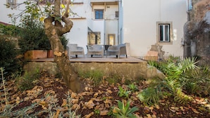 A courtyard with a tree, outdoor seating, and a building with balconies. - Portas de São Bento Apartment (Lisbon)