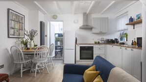 Un espacio habitable compacto con comedor, kitchenette y sofá con cojines.