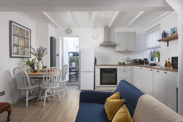 A compact living space with a dining area, kitchenette, and a sofa with cushions.