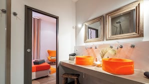 Et badeværelse med to store, orange håndvaske, en træskammel og et spejl over håndvaskene.