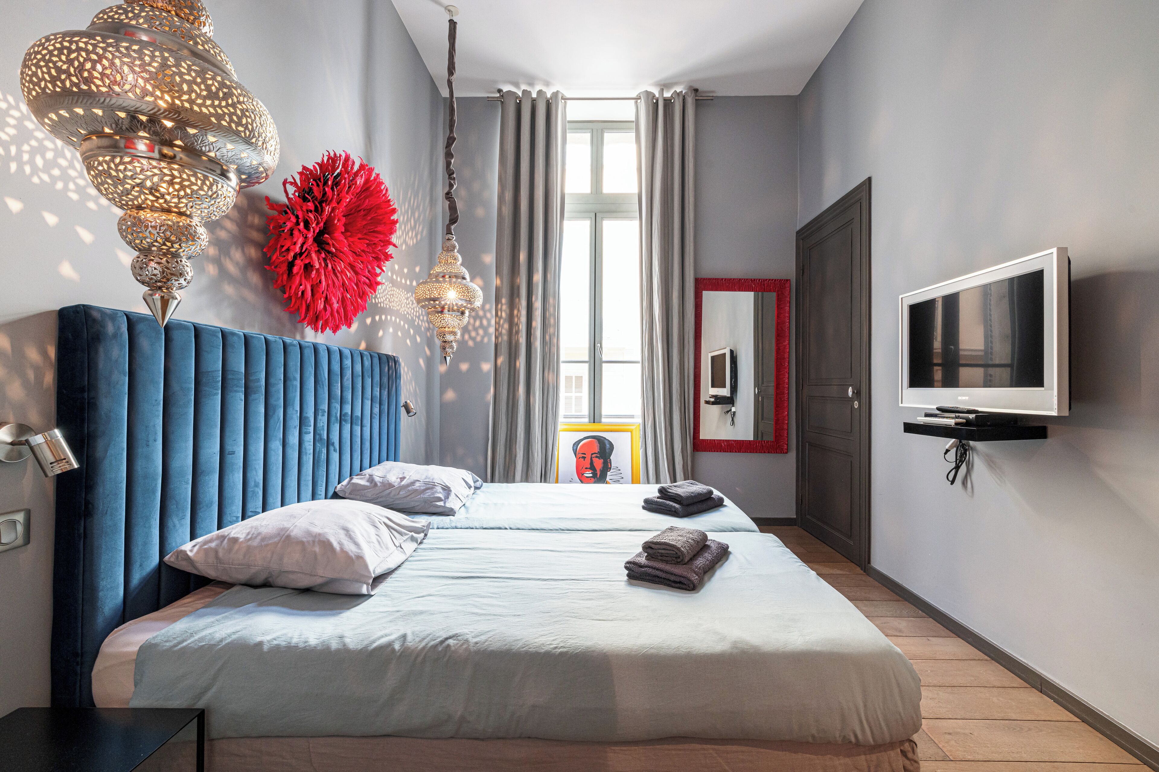 Et moderne hotelværelse med en stor seng, et fjernsyn og en dekorativ lysekrone.