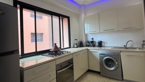 Une cuisine moderne équipée d’un four encastré, d’un lave-linge et d’un évier.