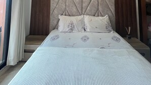 Une chambre avec un grand lit, une tête de lit aux motifs géométriques et une vue sur l’extérieur.