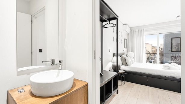 A modern bathroom with a large mirror, a white sink, and a wooden vanity. - GuestReady - Quental Wallpaper near Marquês Square (Porto)