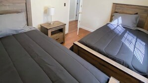 Une chambre avec deux lits, un ventilateur de plafond et une table de chevet avec une lampe.