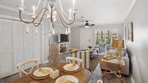 A dining area with a chandelier, white furniture, and a view of the living room. - Portside Sg2- Seabreeze Townhome (Panama City Beach)