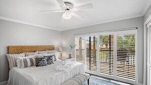 A bedroom with a large bed, a ceiling fan, and a view through the window blinds. - Portside Sg2- Seabreeze Townhome (Panama City Beach)
