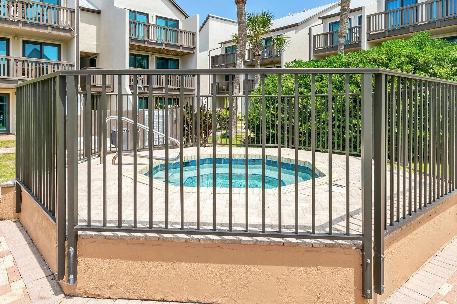 A swimming pool surrounded by a metal fence, with a building in the background.