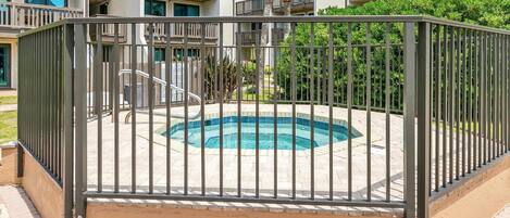 A swimming pool surrounded by a metal fence, with a building in the background.