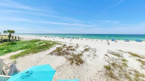 Une plage avec un ciel dégagé, un rivage sablonneux et quelques parasols.
