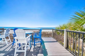 A wooden deck with chairs and tables overlooking a beach. - Sunset Sanctuary (Panama City Beach)