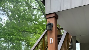 Eine Holztreppe mit weißer Handlauf und einer schwarzen Laterne an der Pfosten, die zu einer überdachten Veranda führt.