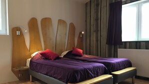 A bedroom with two beds, wooden headboards, a window with curtains, and a wooden floor. - Défiplanet' (Dienne)