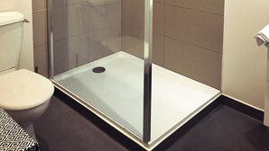A glass-enclosed shower stall with a handheld showerhead and a wall-mounted control panel. - Défiplanet' (Dienne)