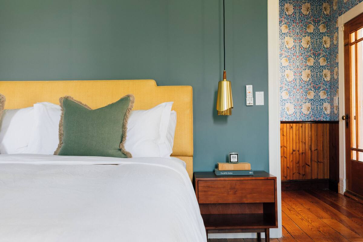 Une chambre à coucher avec un lit, une table de chevet et une lampe fixée au mur.