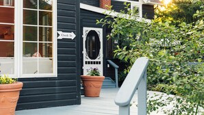 A black building with a white door, a check-in sign, and a potted plant on the porch. - Silas House (Lexington)