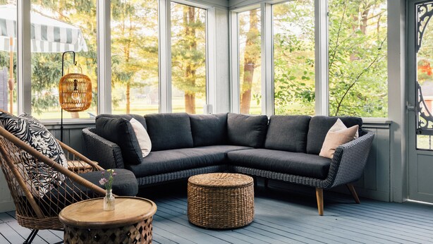 A modern living room with a sectional sofa, a wicker ottoman, and a rattan chair. - Silas House (Lexington)