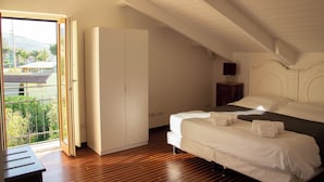 A bedroom with a large bed, a wardrobe, and a view of a balcony with a house and trees. - Comfortable Living Space in Sorrento (Sant'Agnello)