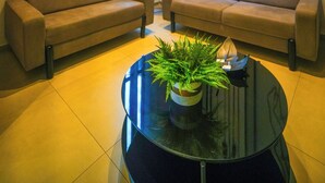 A modern living room with two sofas, a coffee table with a plant, and three framed artworks on the wall. - Hotel Coroados Foz Express (Foz do Iguaçu)