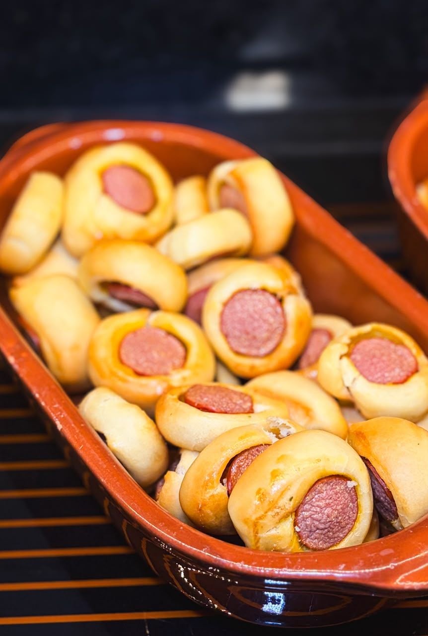 A ceramic dish containing sausage rolls.